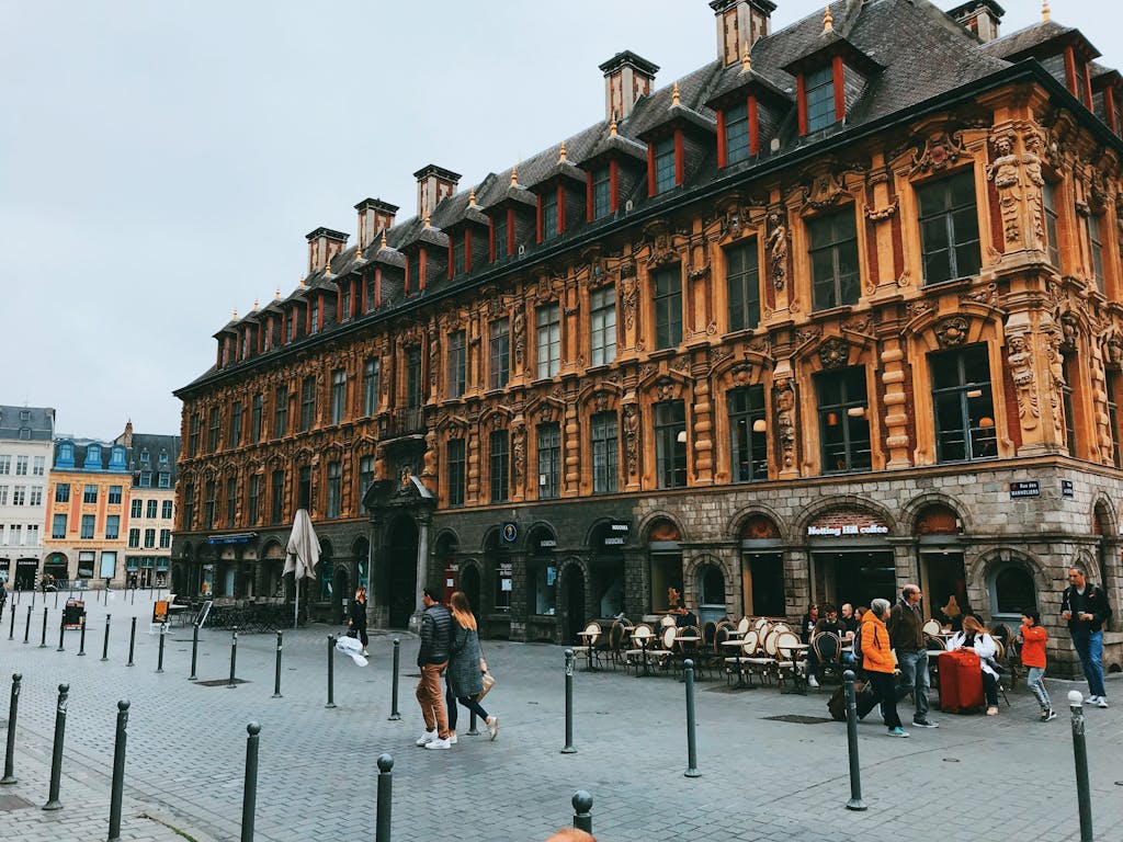 A bustling European square with a historic building and people interacting, captured during the day.