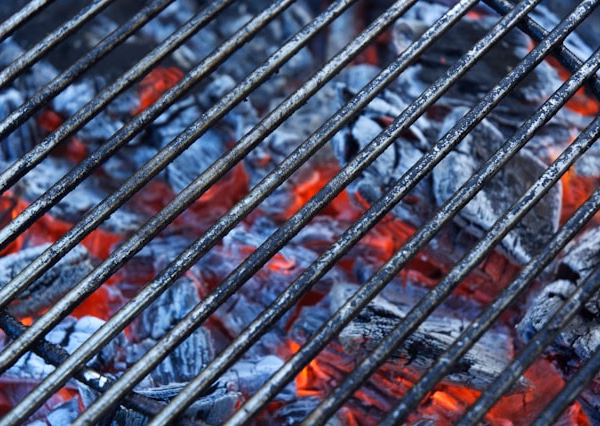 Expert utilisant une brosse en laiton pour nettoyer grille barbecue en fonte.