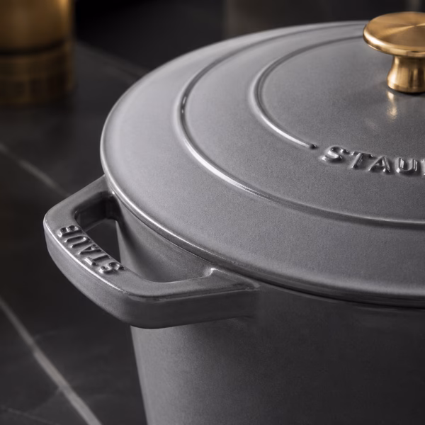 Femme de ménage experte montrant comment nettoyer une cocotte en fonte avec soin.