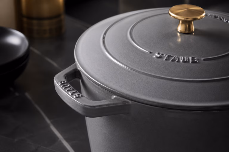 Femme de ménage experte montrant comment nettoyer une cocotte en fonte avec soin.
